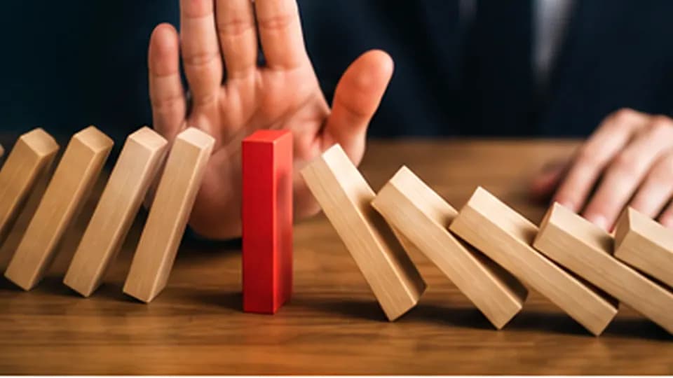 Formation – Formation objections commerciales : écouter, qualifier et répondre avec justesse – Présentation Une main stoppe une série de dominos pour représenter le traitement méthodique des objections commerciales.