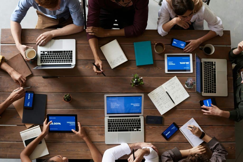 Groupe de personne travaillant sur une table avec ordinateur et cahier vu d'en haut